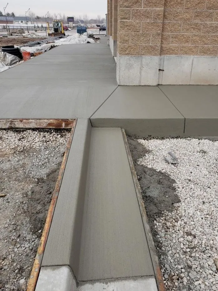 Freshly poured concrete walkway and foundation along a building exterior