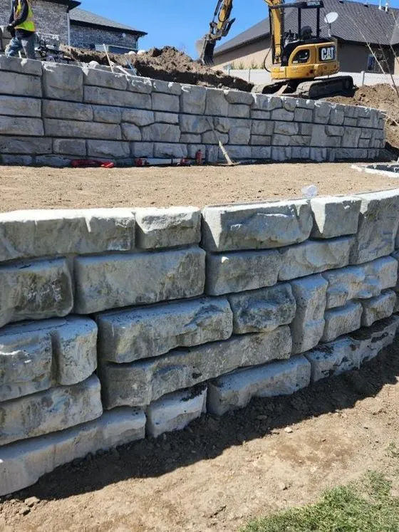 Stone retaining wall under construction with excavation equipment
