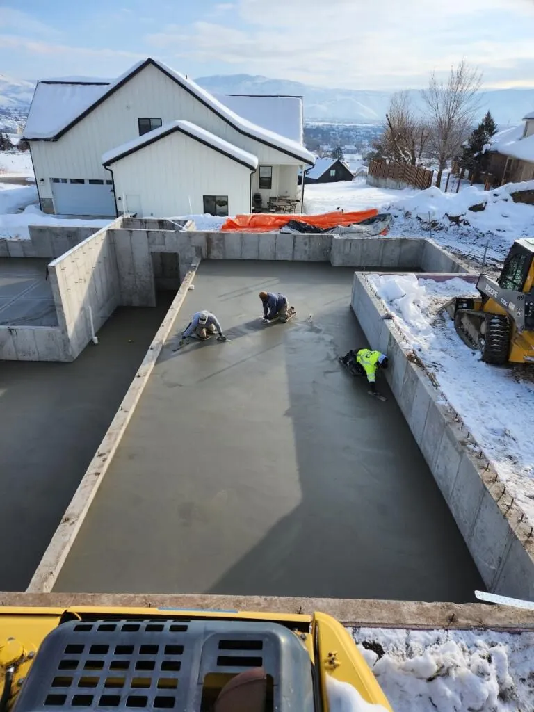 Crew finishing a concrete basement floor in winter