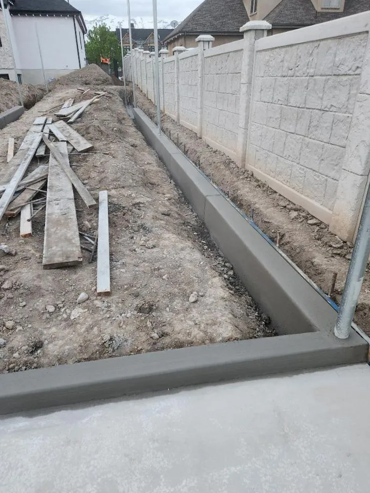 Concrete curbing poured along a fence line