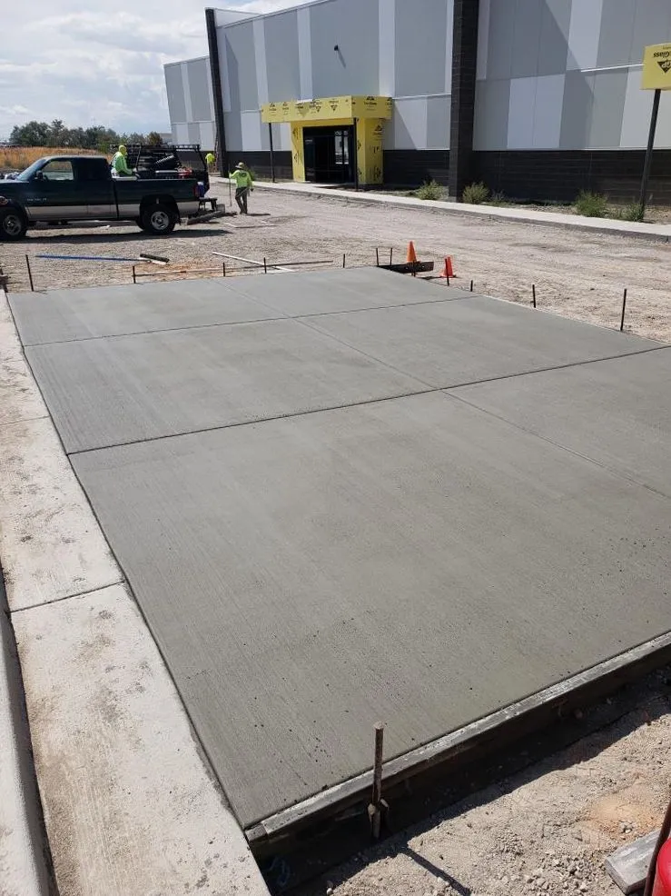 Freshly poured commercial concrete pad next to a building