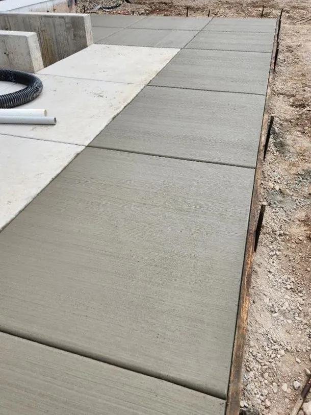 Concrete patio extension freshly poured next to a home