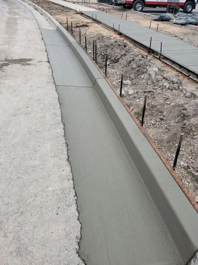 Concrete curb being poured along a roadside