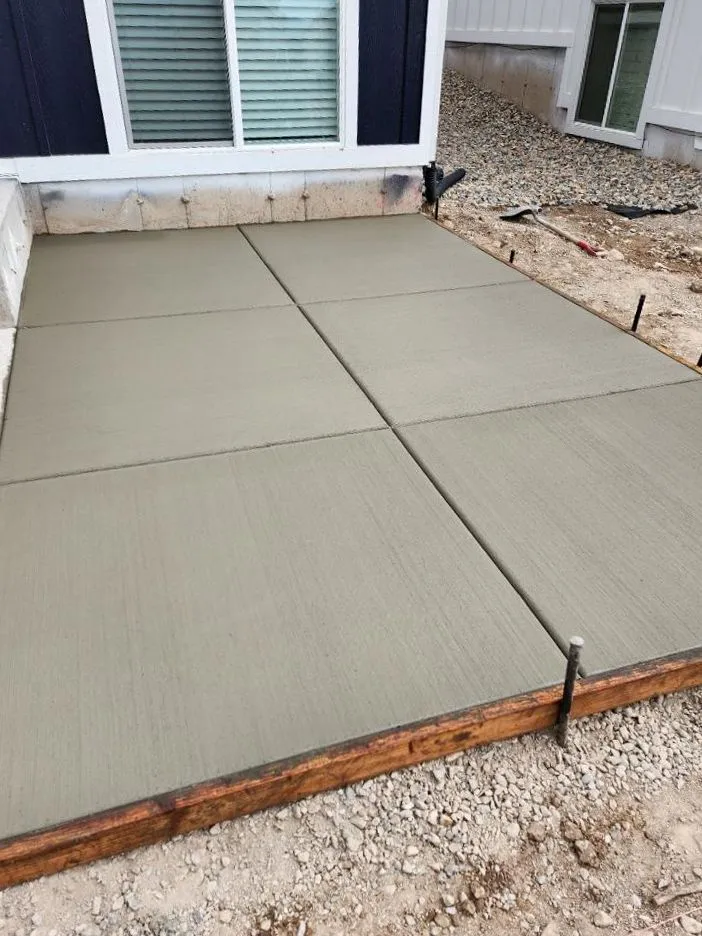 Freshly poured concrete patio slab next to a house