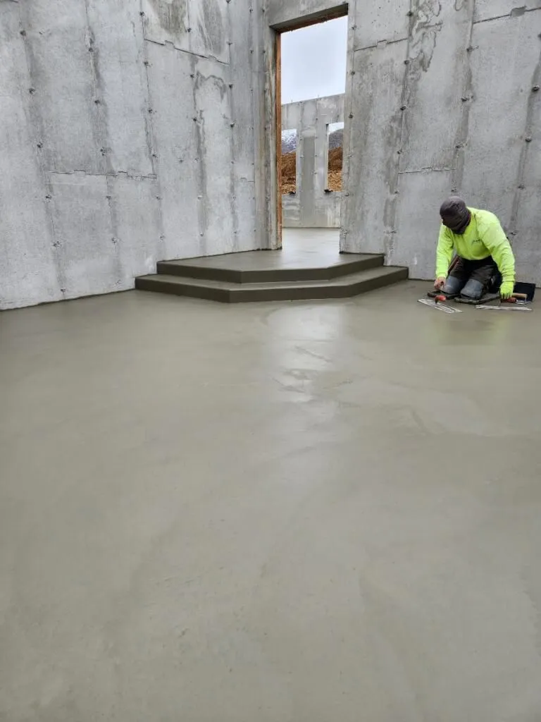 Worker finishing a basement concrete floor near stepped doorway