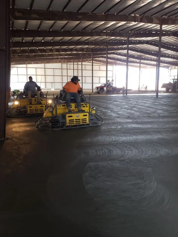 Workers operating ride-on trowels on a large commercial floor